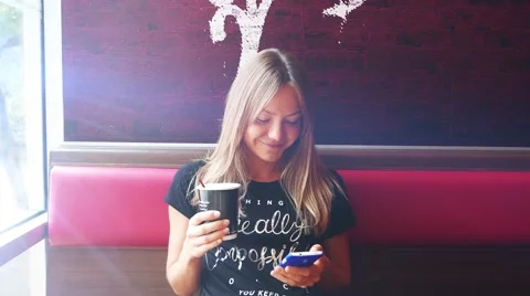 Woman using smartphone in cafe drinking coffee smiling Stock Footage 56769328