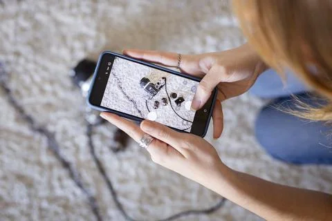 Woman using smartphone capturing flat lay vintage camera 스톡 사진