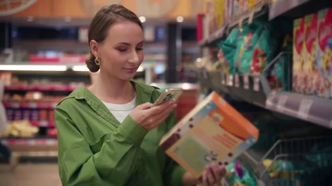 Woman using smartphone for checking product information in supermarket Stock Footage 285026413