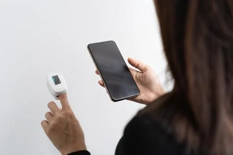 Woman using smartphone device, checking blood oxygen level measure with digit Stock Photos