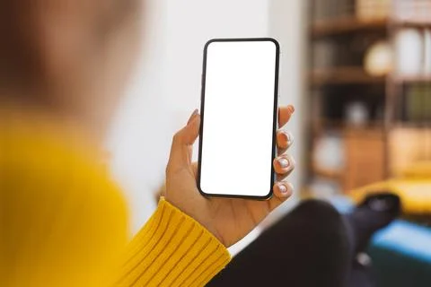 Woman using smartphone frameless mockup blank screen in home interior. Workin Stock Photos