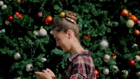 Woman using smartphone in front of decorated Christmas tree... Stock Footage 323733053