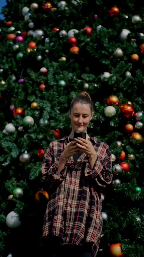Woman using smartphone in front of decorated Christmas tree... Stock Footage 323733238