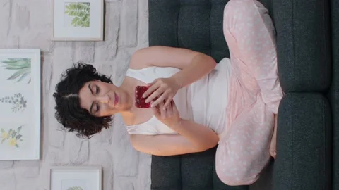 Woman using a smartphone is lying on the sofa. Video for the vertical story. Stock Footage 141115147