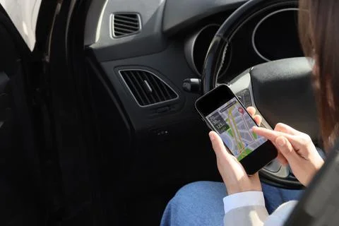 Woman using smartphone navigation app in car for route planning and travel gu Stock Photos
