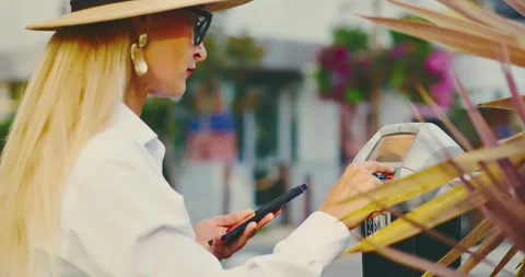 Woman Using Smartphone to Pay at Parking Meter Outdoors Stock Footage 323339655