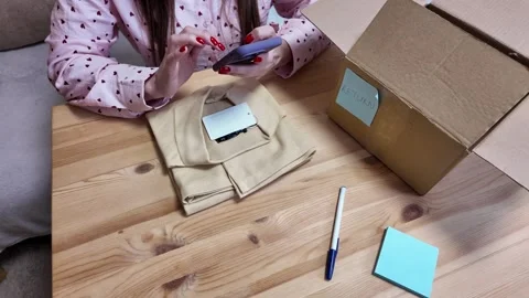 Woman using smartphone to return clothes bought online, view from above Stock Footage 305025833