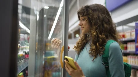 Woman using smartphone to scan grocery product in supermarket Stock Footage 303606971