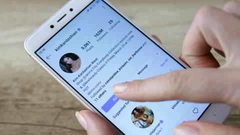 Woman Using Smartphone With To Scroll Instagram Profile Of Kim Kardashian. 스톡 동영상 126605871