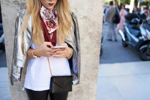 Woman using smartphone, silver jacket over shoulders, crop Stock Photos