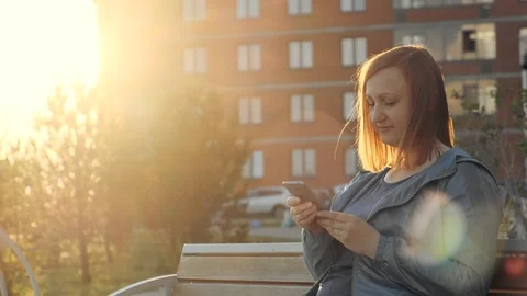 Woman using smartphone sitting on bench in city Stock Footage 111192004