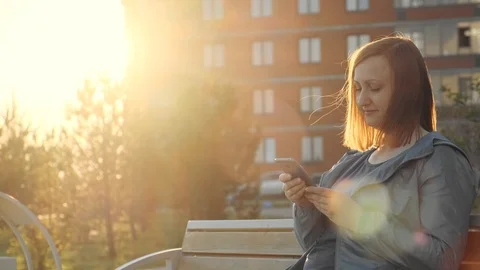 Woman using smartphone sitting on bench in city 스톡 동영상 111192258