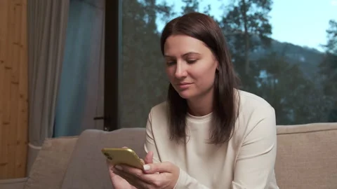 Woman using smartphone on sofa in mountain chalet Stock Footage 303498795