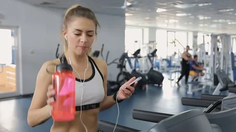 Woman using smartphone to text message while walking on gym treadmill Stock Footage 74837337
