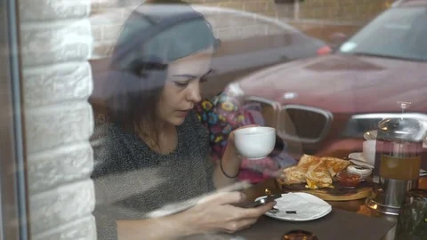 Woman using smartphone touchscreen in cafe drinking coffee. The girl is sitting Stock Footage 82062064