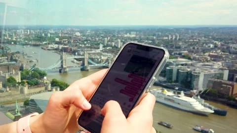 Woman Using Smartphone with Tower Bridge and London Skyline in Background, 4K 스톡 동영상 202211251