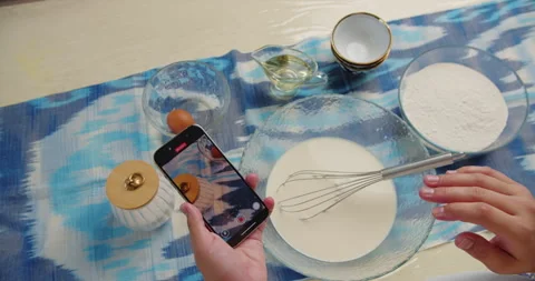 Woman using smartphone while cooking with ingredients Stock Footage 318172746
