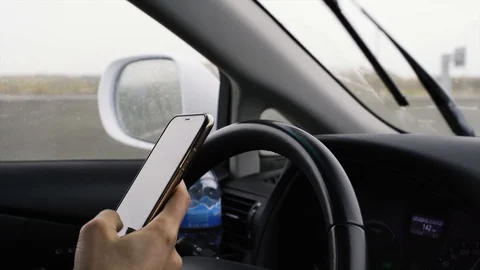 Woman using smartphone while driving in rainy day Stock Footage