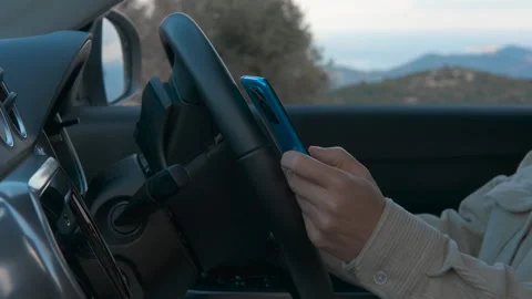 Woman using smartphone while driving modern car Stockbeeldmateriaal 327482966