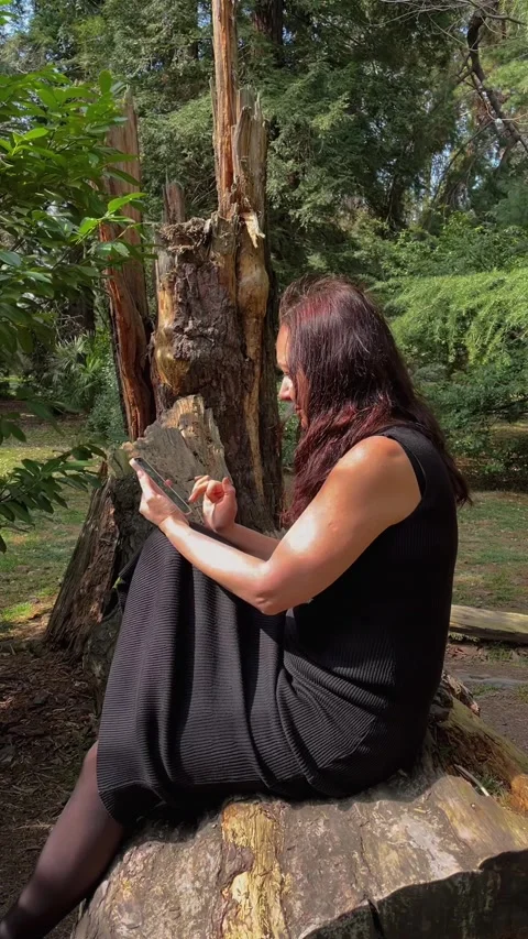 Woman using smartphone while examining fallen tree in forest Stock Footage 336867097