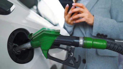 Woman using smartphone while her car is refueling. Slow motion Stock Footage 121416159