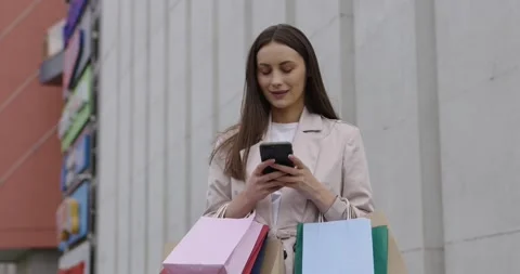 Woman using smartphone while holding shopping bags Stock Footage 162075115