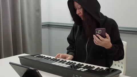 Woman using smartphone while playing keyboard at table in studio Stock Footage 301273847