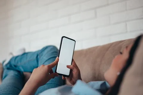 Woman using a smartphone while relaxing on the couch at home Stock-Fotos