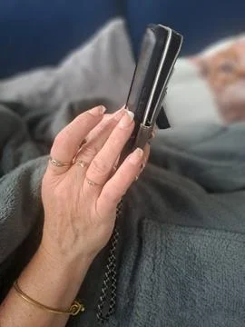 Woman using a smartphone while relaxing at home. Stock Photos