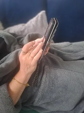 Woman using a smartphone while relaxing at home. Stock Photos