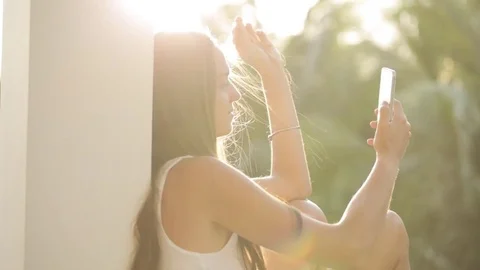 Woman using smartphone while sitting on terrace with garden on background Video stock 73415666