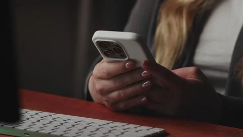 A woman is using a smartphone while sitting at a work desk in an office Stock Footage 277043076