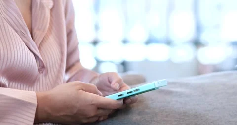 Woman using smartphone while sitting on sofa at home. copy space, online Video stock 335804767