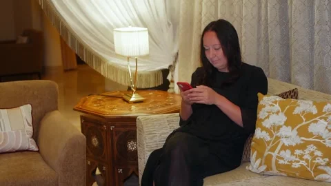 Woman using smartphone while sitting on sofa in elegant living room Video stock 341424014