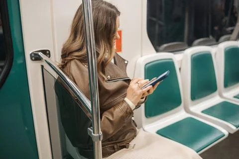 Woman Using Smartphone While Sitting on Subway Train During Daytime Commute in Stock Photos