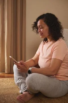 Woman using smartphone while sitting on floor at home Stock-Fotos