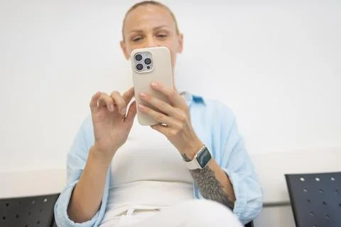 Woman using a smartphone while sitting, interacting with mobile technology .. Stock Photos