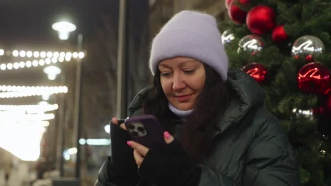 Woman using smartphone while standing by Christmas tree in city Stock Footage 301842850