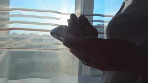 Woman using smartphone while standing by window Stock Footage 336490687
