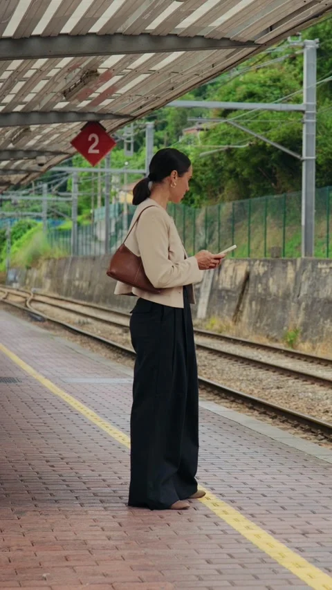 Woman Using a Smartphone While Waiting on a Train Station Platform Stock Footage 338344561