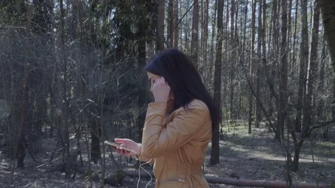 Woman using smartphone while walking through the forest Stock Footage 75875034