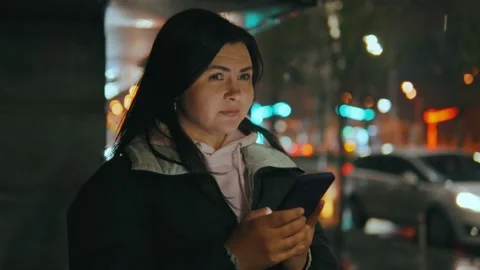 Woman using smartphone while walking through evening city streets Stock Footage 238956156