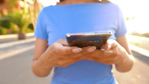 Woman using smartphone while walks on a palm street at sunset Stock Footage 112523145
