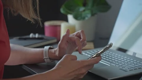 Woman using smartphone while working at desk with laptop Stock Footage 313301038