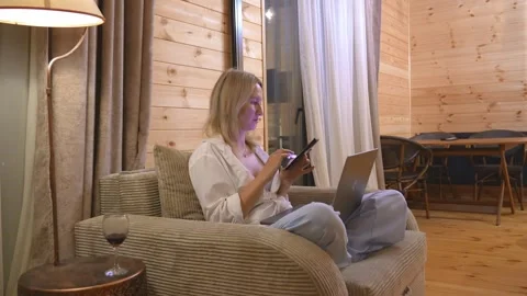 Woman using smartphone while working on laptop at home Stock Footage 342075568