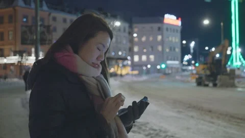 Woman Using Smartphone in Winter City Scene at Night Stock Footage 327082653