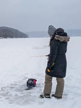 Woman Using Sonar While Ice Fishing on a Vast Frozen Lake During Snowfall Stock Photos