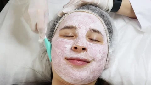 Woman using spatula to apply moisture anti-wrinkle mask before facial foundation Stock Footage 278100559