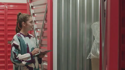 Woman Using Tablet and Instructing Husband in Self Storage Stock Footage 259827900