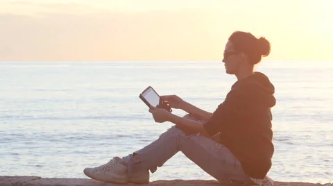 Woman using a tablet on the beach during sunset Stock Footage 61436284